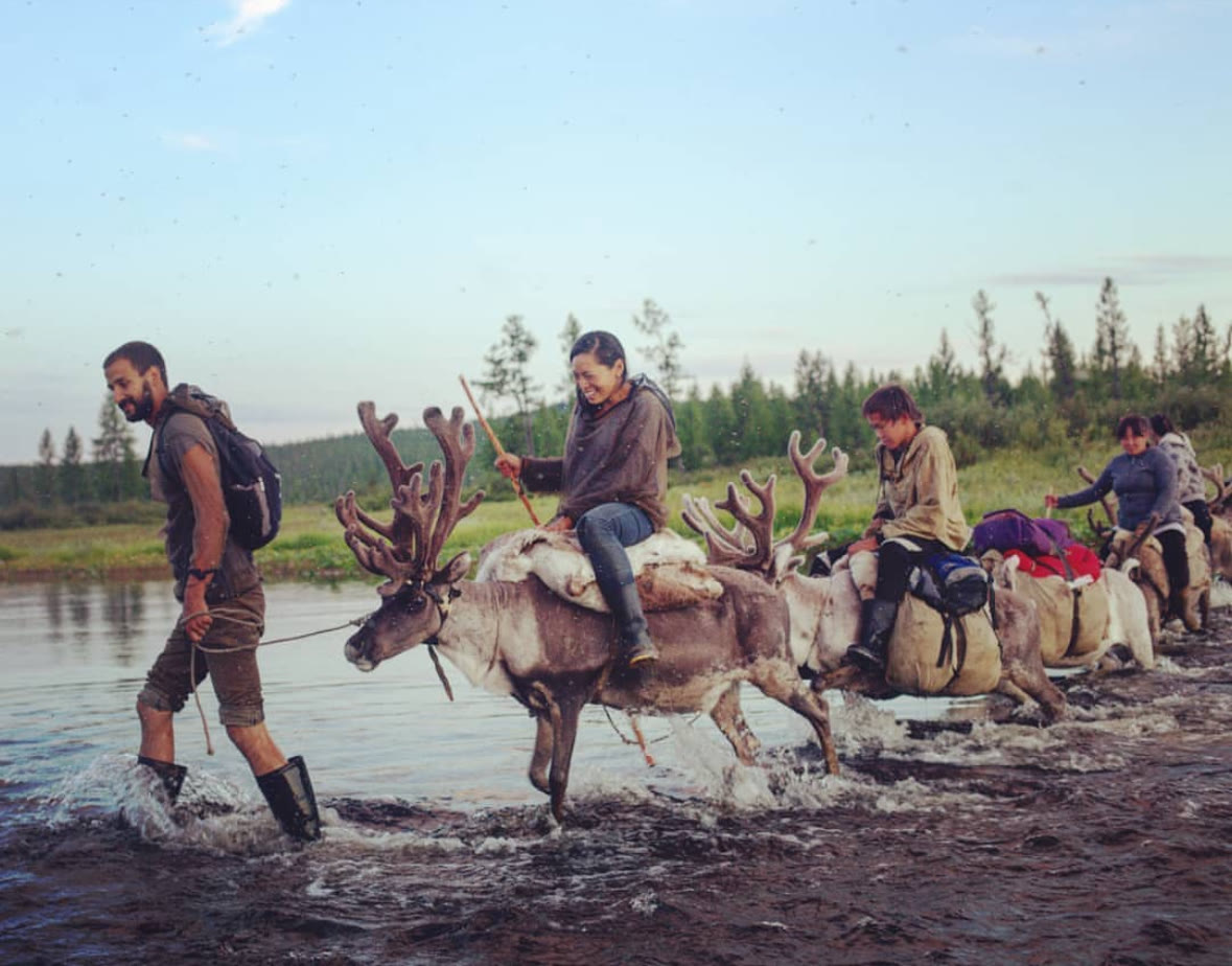 Jordan leading a reindeer caravan across a river in Siberia