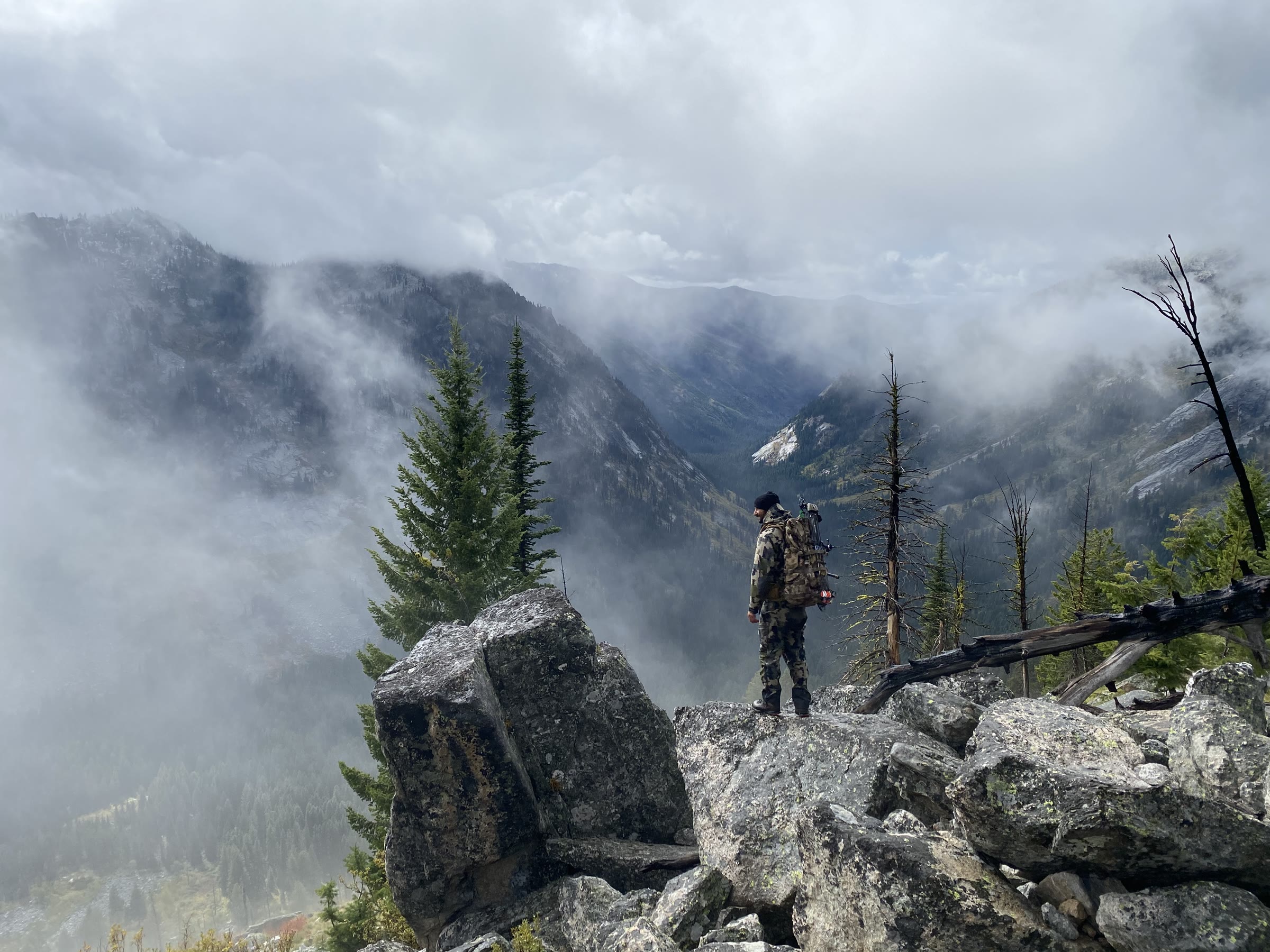 Jordan Jonas on a boulder ridge above a foggy mountain valley